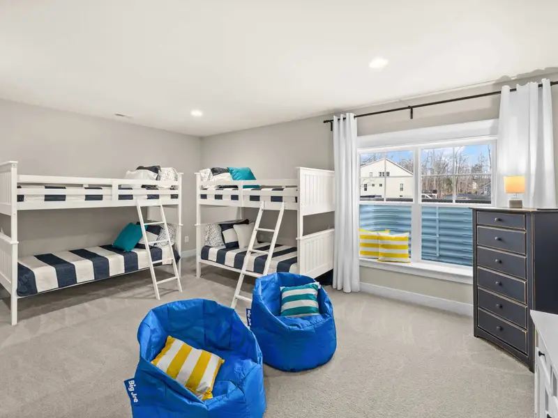Bunk Room - Two sets of white twin bunk beds with colorful bedding and blue bean bag chairs, designed to be the kids' favorite room.