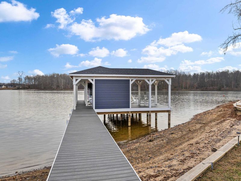 Boathouse - The covered boathouse extends over the water with a long dock walkway and Adirondack chairs on the upper deck.