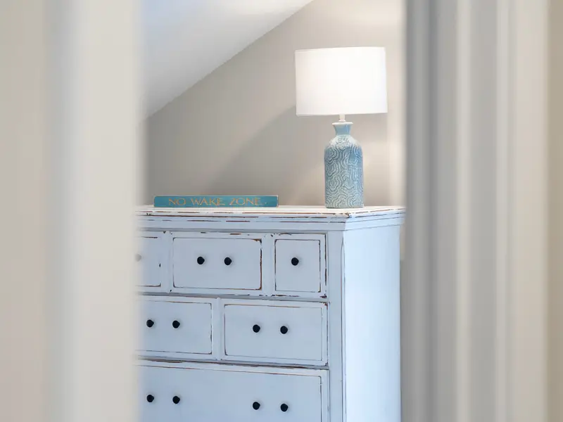 Queen Bedroom - A blue dresser with a 'No Wake Zone' sign and a table lamp bring personality to the upper bedroom.