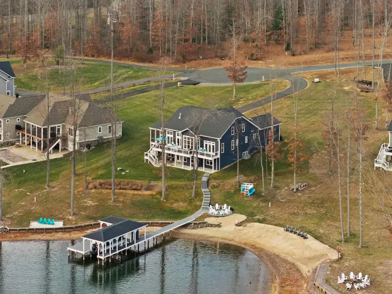 Exterior - The full property from the lake side, fire pit chairs, kayak rack, beach, and boathouse all visible.