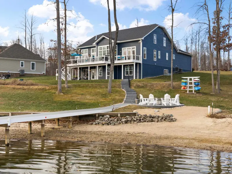 Exterior - The rear of the house from the shoreline shows the multilevel decks, fire pit area, and sandy beach.