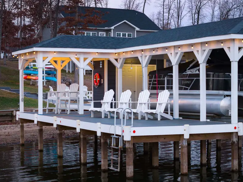 Boathouse - String lights, Adirondack chairs, and the pontoon at rest under the covered dock as the evening settles in.