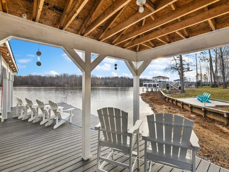 Boathouse - The covered dock deck with Adirondack chairs looking out across the lake, pontoon slip on the left.