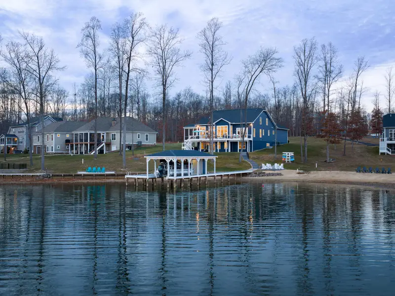 Exterior - A tranquil water-level view shows the full property, boathouse, dock, and house reflected in the still cove.