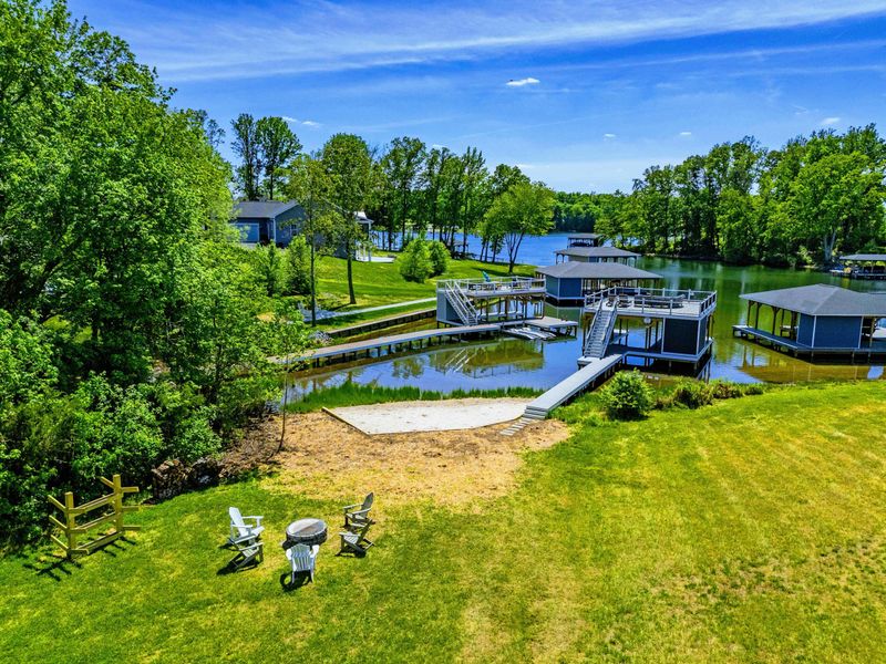 Aerial Backyard - Fire pit on the lawn, dock and beach below, the cove opening to open water on the horizon.