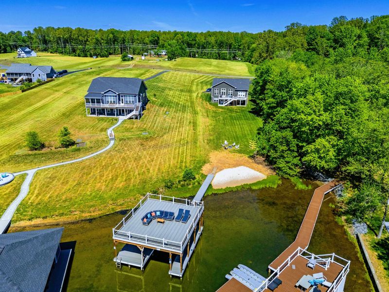 Aerial Lakefront - Sun deck, dock, and beach line up against the cove, with the house tucked into mature trees behind.