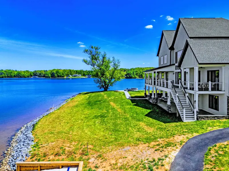 Backyard & Beach - Sloping lawn from the screened porch down to the lake, with the rocky shoreline framing the view.