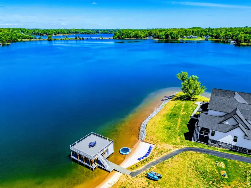 Exterior - Closer aerial showing the dock's upper deck, kayak gear, and hot tub patio tucked into the lake side of the home.