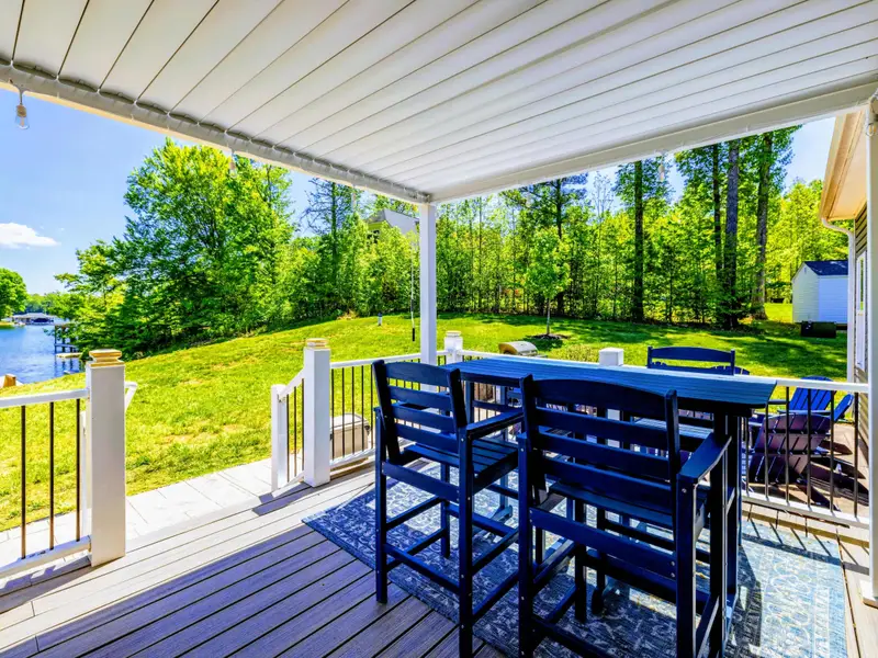 Back Porch - Bar-height table under the pergola, lake views off the left rail, yard rolling down to the water.