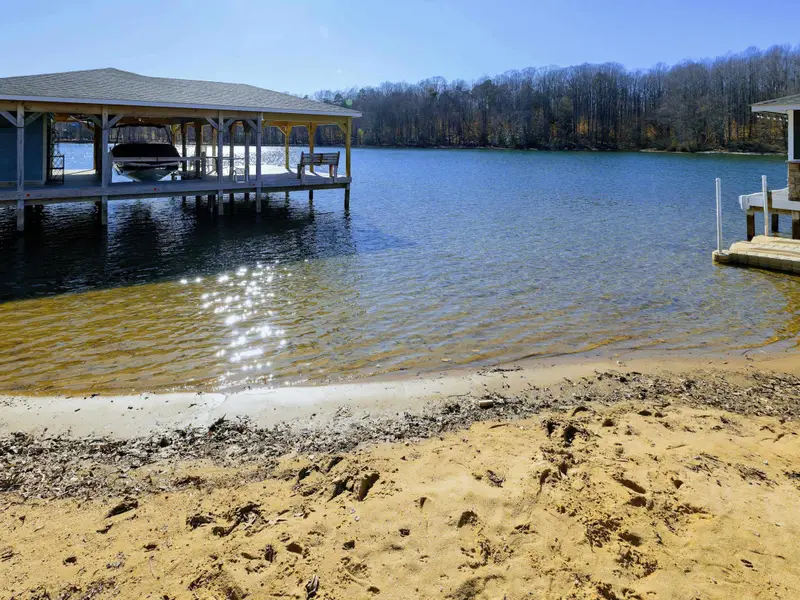 Backyard - The home sits up the slope from the waterfront, with the dock, sandy beach, and boathouse spread out below.