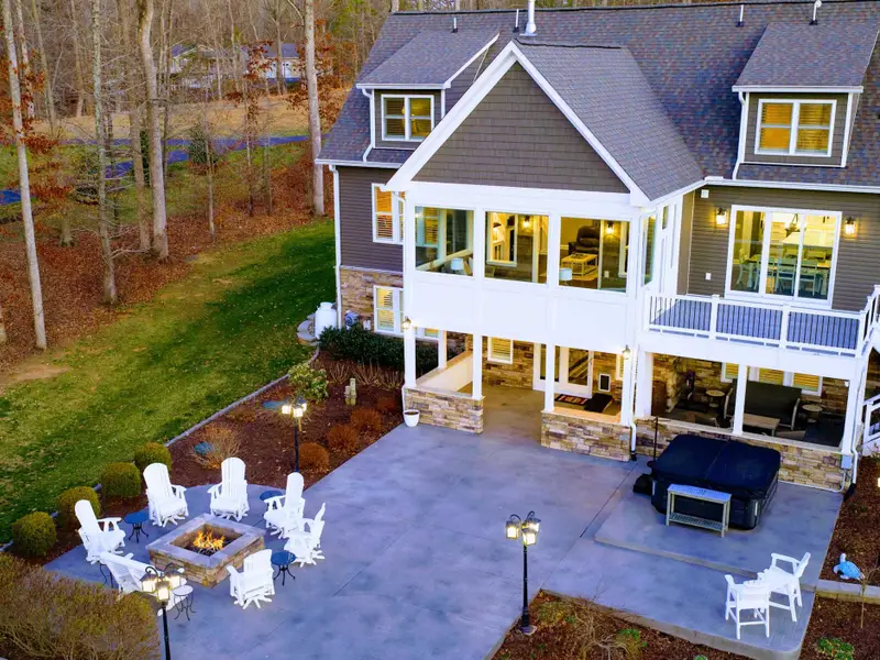 Patio - Stone patio with fire pit and Adirondack chairs anchors the back of the home, hot tub and screened sun room just above.