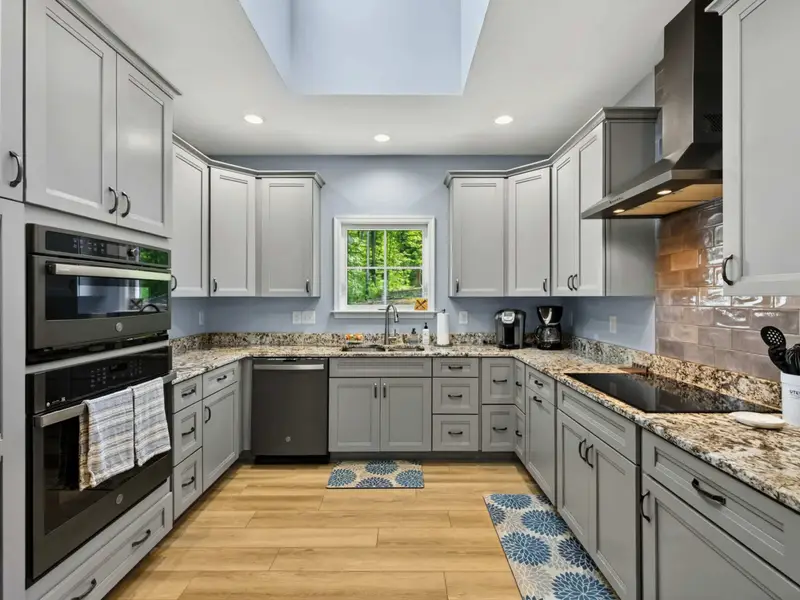 Kitchen - Gray shaker cabinets, granite counters, wall oven with microwave above, and induction cooktop on the opposite counter.