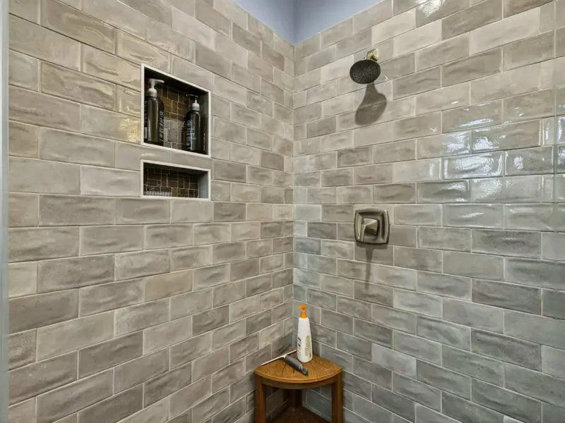 Suite 1 Bath - Walk-in tile shower with brass fixtures and double vanity.