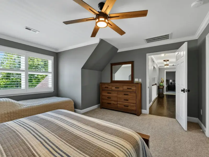 Upper Level Bedroom - Queen and twin paired in one room, a dresser tucked into the angled dormer wall, and the upstairs landing visible beyond the door.