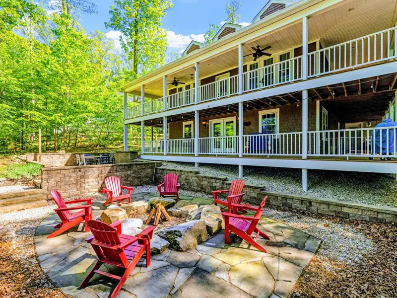 Patio - The home tucked into its wooded setting, with outdoor space spilling down to the water.