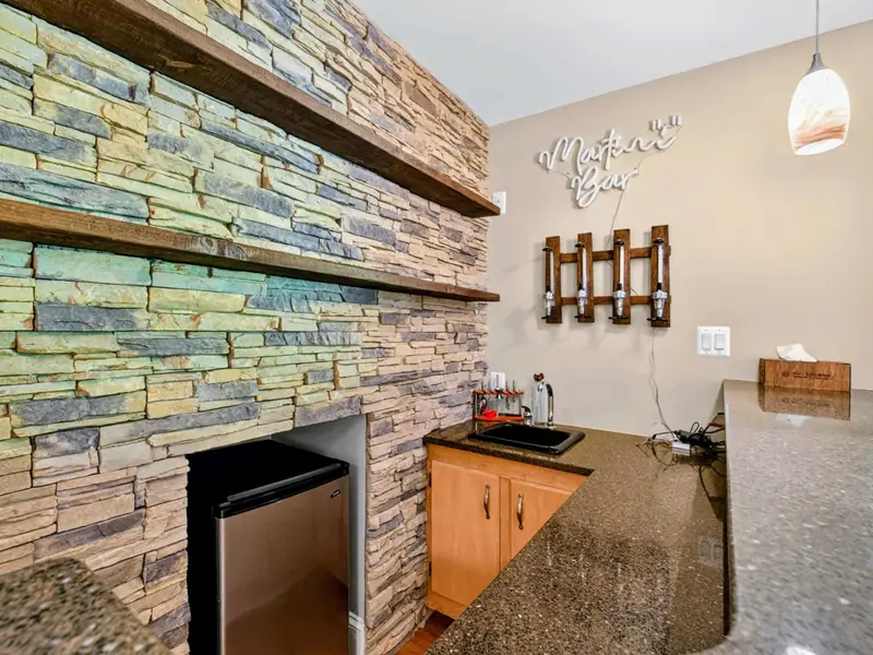 Wet Bar - Floor-to-ceiling stone, granite counter, and a built-in fridge make this the favorite gathering point.