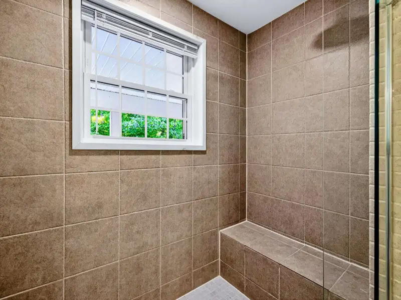 Primary Bath - Tiled walk-in shower with built-in bench and clear glass enclosure.