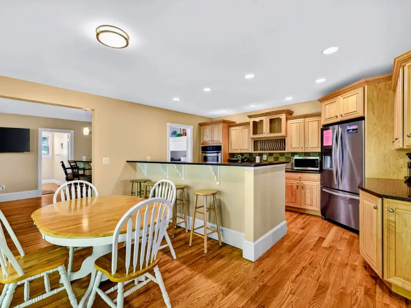 Kitchen - Honey-oak cabinetry, dark stone countertops, and a large island ready for prep and conversation.
