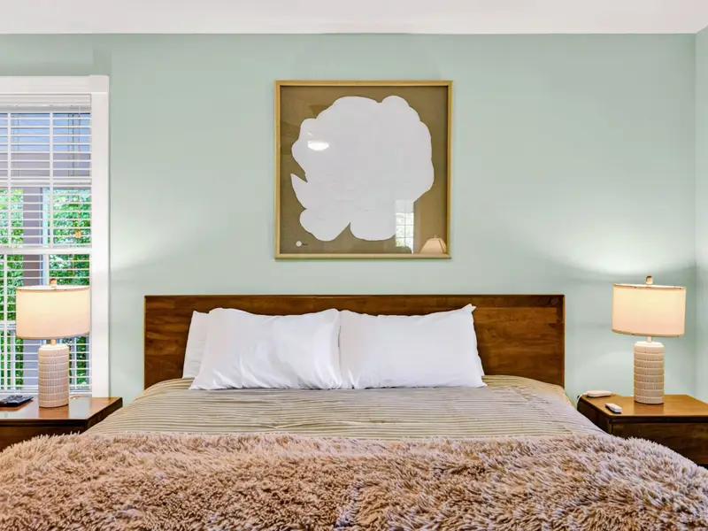 Primary Suite - Carved wood headboard and a decorative mirror give the room a polished, calming feel.