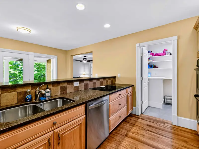 Kitchen - Stainless cooktop, custom hood, and oak cabinetry give the room its warm, classic feel.
