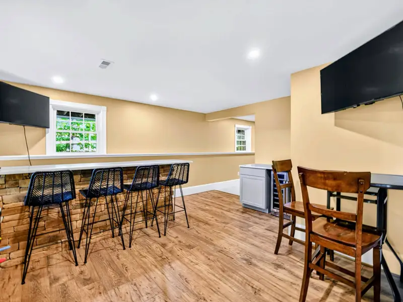 Game Room - Wet bar with high-top stools, mounted TV, and a clear line of sight to the games beyond.