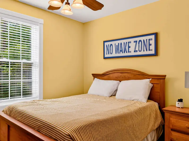 King Bedroom - Traditional wood-frame king bed with classic linens, framed by two windows of natural light.