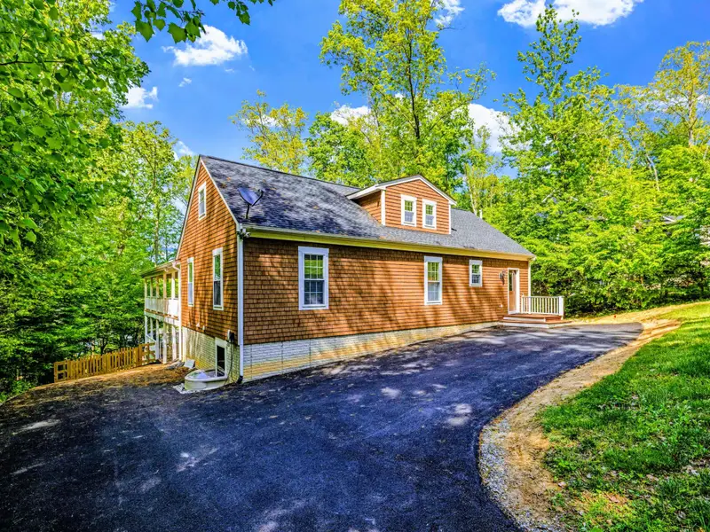 Exterior - The home rises behind a long paved driveway, tucked into mature trees for natural privacy.