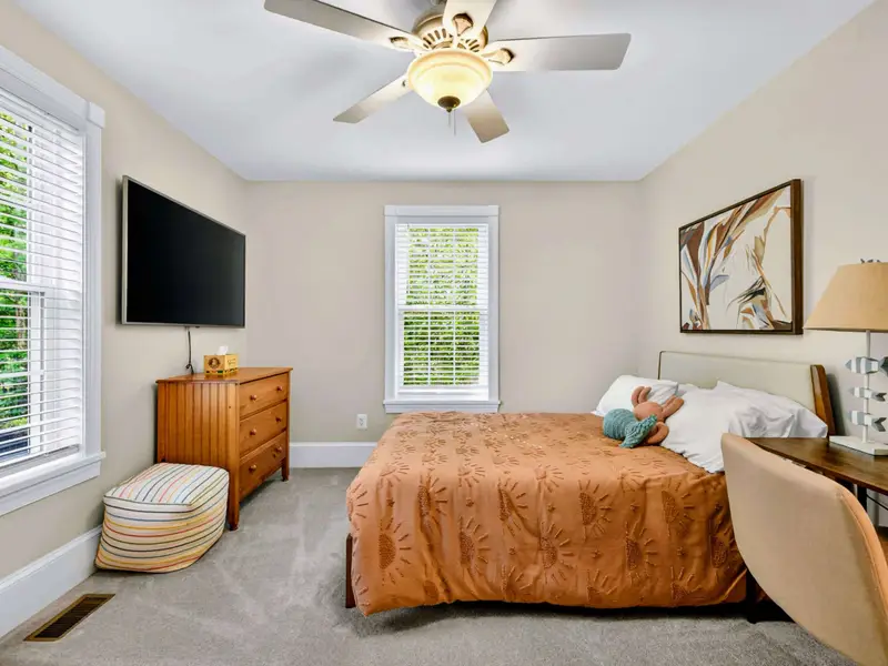 King Bedroom - Wall-mounted TV, generous storage, and plenty of natural light through the large windows.