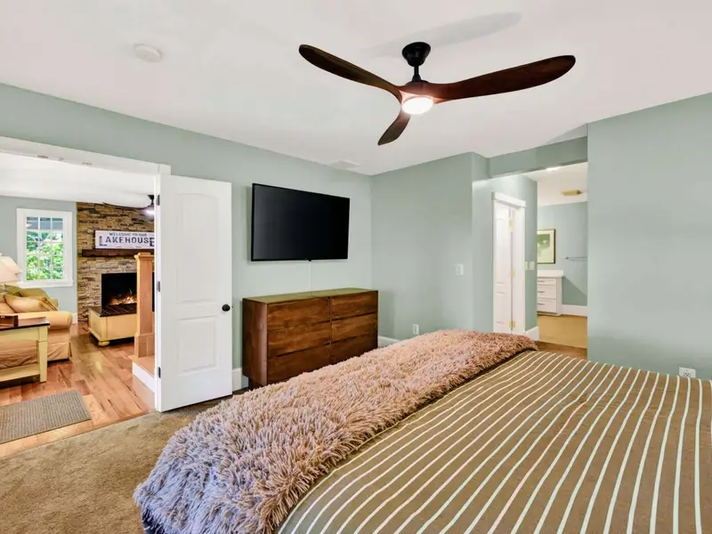 Primary Suite - Wall-mounted TV on one wall, French doors on another, comfort in every direction.