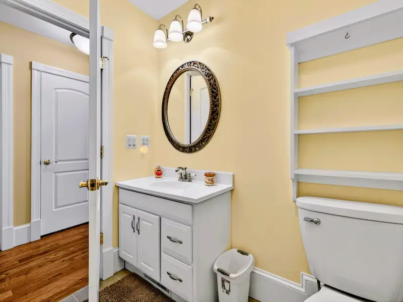 Hall Bath - Sunny yellow walls, decorative round mirror, and open shelving give this main-level bath its own personality.
