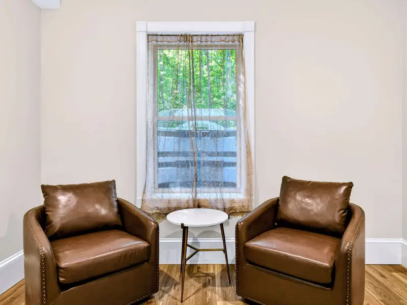 Sitting Area - Two leather club chairs and a window full of trees, perfect for morning coffee or a quiet read.