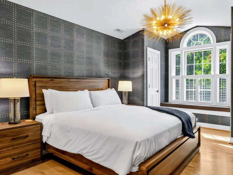 King Bedroom - Wood-frame king bed against the textured dark wall.