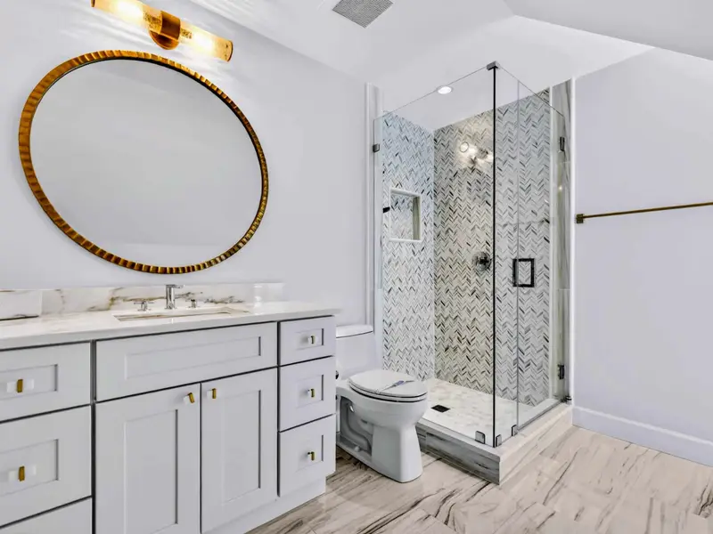 Ensuite Bath - Round mirror and stone-topped vanity in the upper-level ensuite (off the moody bedroom).