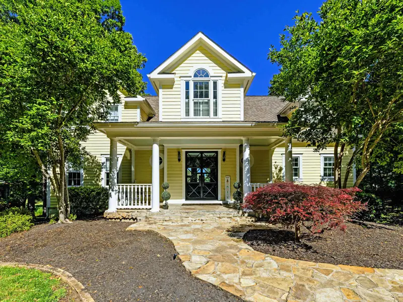 Front Facade - The home's traditional yellow exterior, columned porch, and inviting front entry.