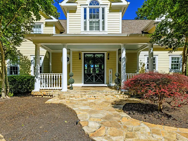Front Porch - Stone steps lead up to a deep front porch with classic columns.