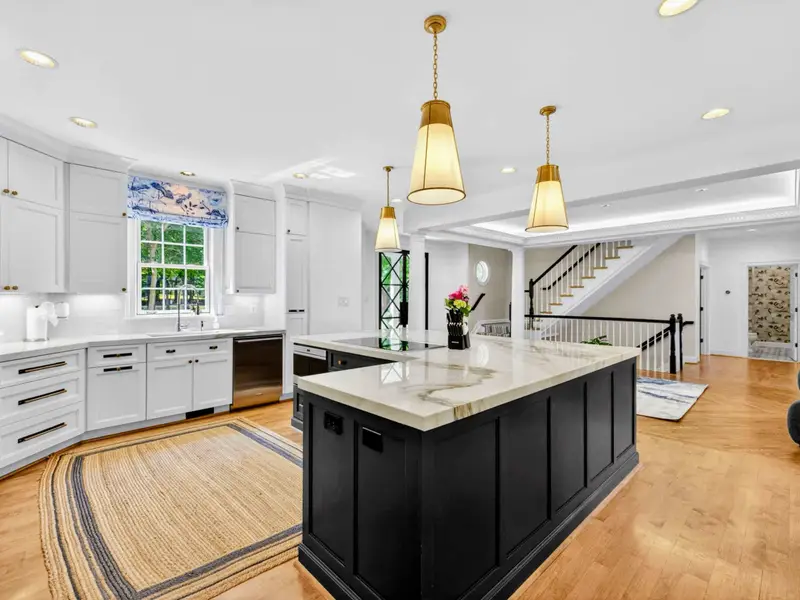 Kitchen - White uppers, navy island, and brass pendants give the kitchen its polished finish.