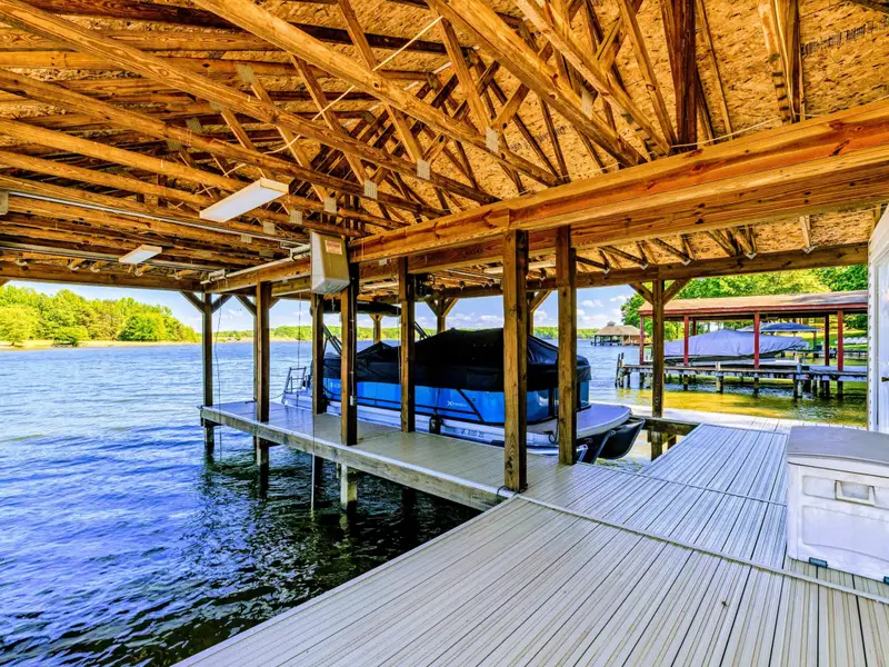 Boat Dock - Vaulted wood framing under the dock roof, the lake visible through every opening.