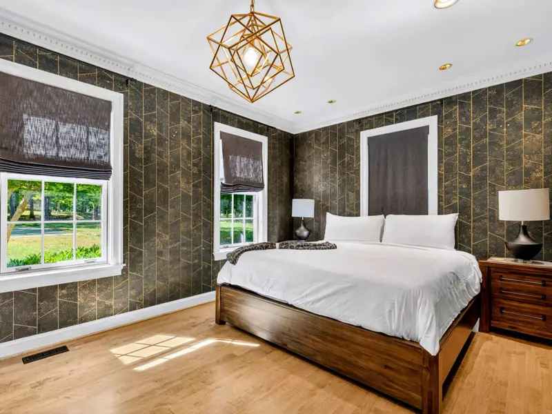 King Bedroom - Front-facing room with king bed and bright wall of windows.