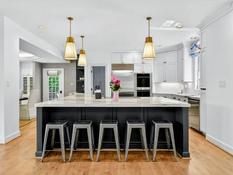 Kitchen - Wide view of the chef's kitchen with seating at the island and full appliance wall behind.