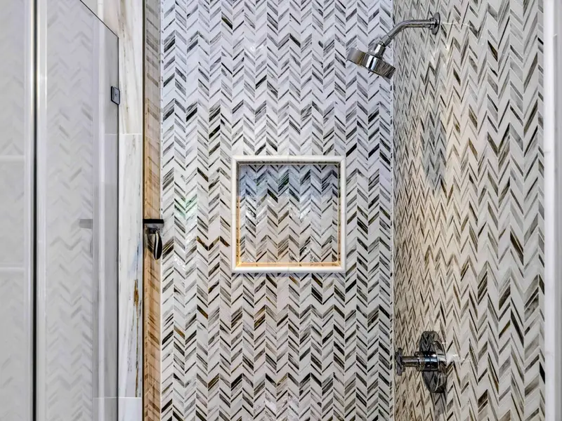 Hall Bath - Herringbone marble walk-in shower with built-in niche.
