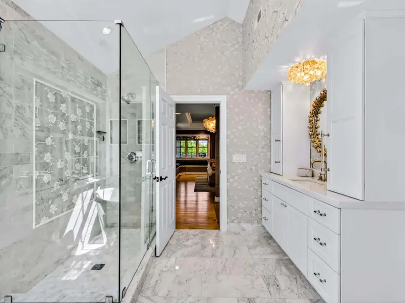 Primary Bath - Walk-in marble shower with glass enclosure and quality fixtures throughout.