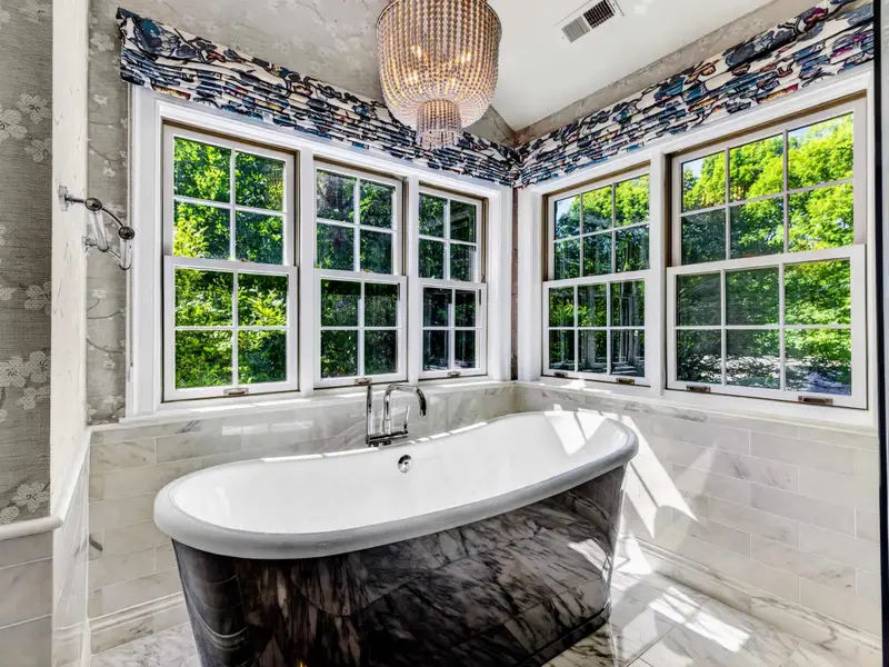 Primary Bath - The soaking tub anchors the primary bath, with marble underfoot and bright daylight.