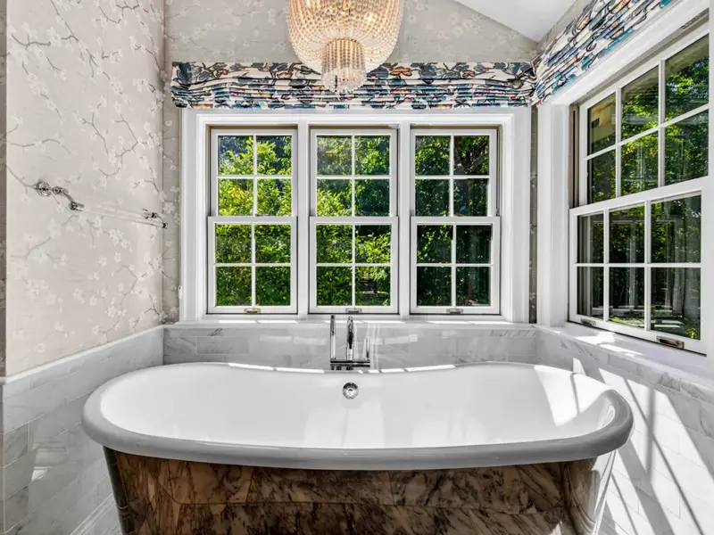 Primary Bath - Freestanding soaking tub beneath a wall of windows looking into the trees.
