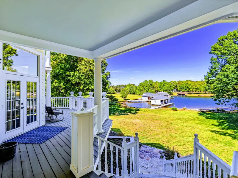 Deck - Covered porch with a large square dining table and direct lake views past the railing.