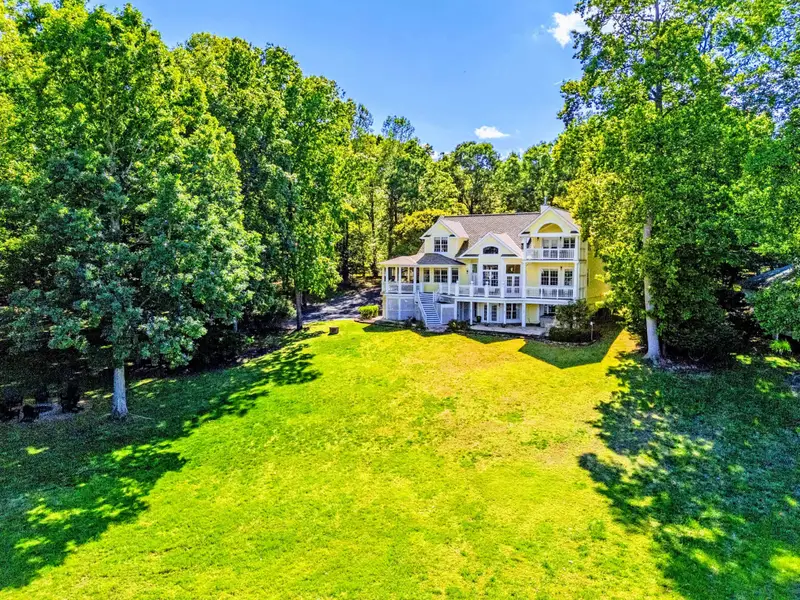 Exterior - Back of the home framed by mature trees, looking up from the lakefront lawn.