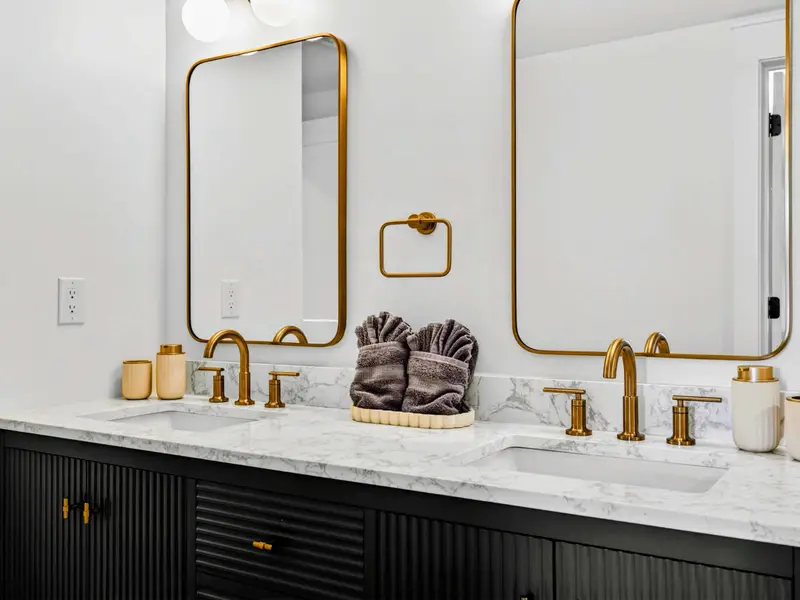 Lower Ensuite - A fluted double vanity with marble counters and brushed-gold fixtures brings a boutique-hotel feel downstairs.