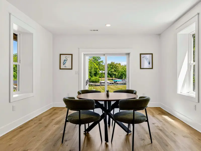 Lakeside Nook - A round table for four sits at the sliding doors, an easy spot for cards, snacks, or breakfast with a lawn-and-lake view.