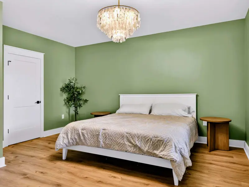 Lower King Suite - Soft green walls and a capiz chandelier give the walkout-level king room a calm, coastal feel.