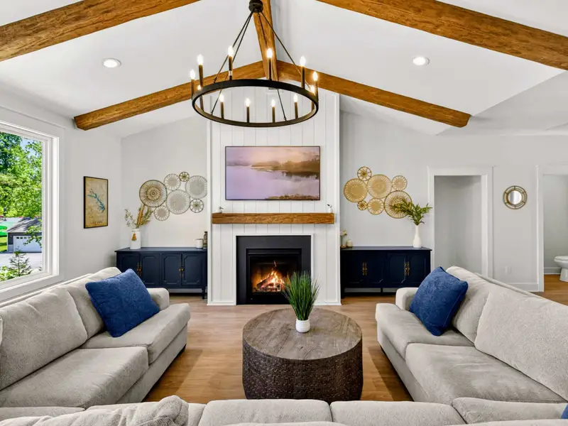 Great Room - Twin sofas face the fireplace and Smart TV beneath a wrought-iron chandelier, with gold accents and a lake-view window framing the room.