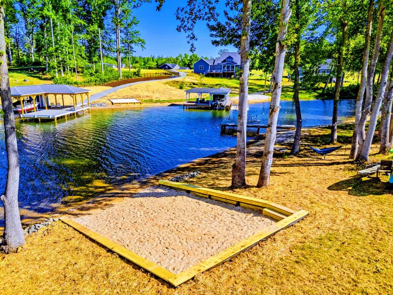 Aerial - Soft sand at the water's edge, a private dock just to the side, and the quiet cove guests come back for.